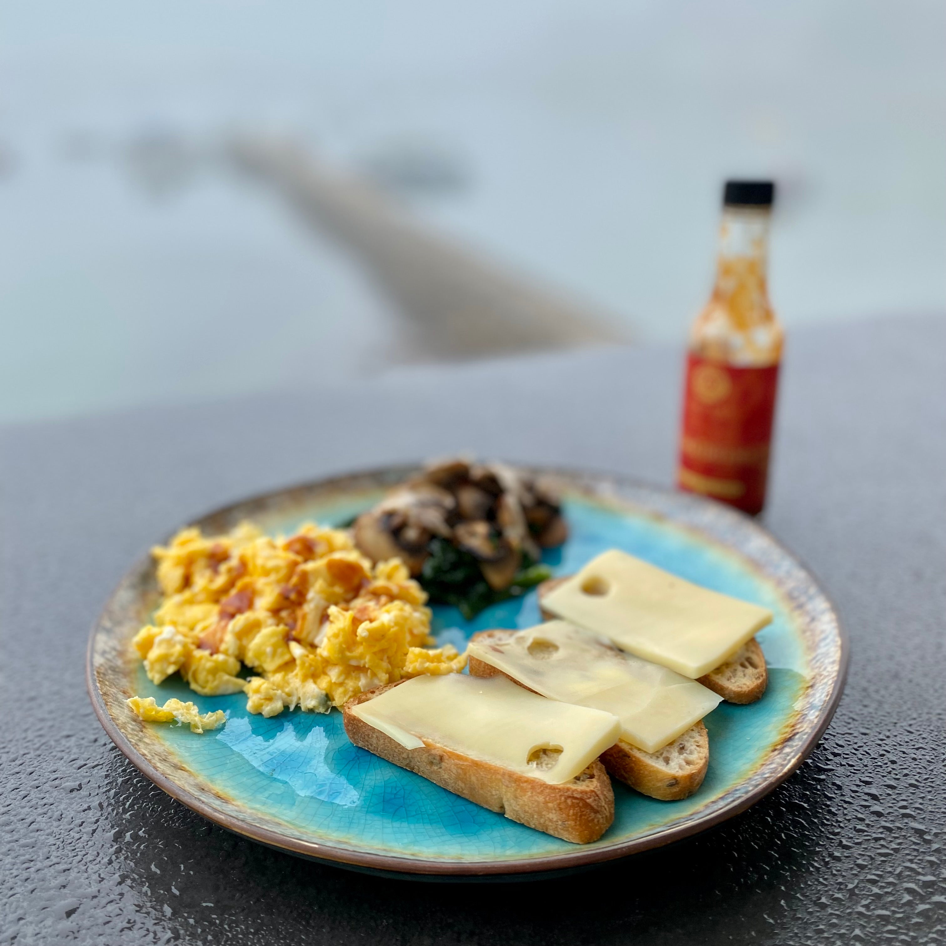 A bottle of Alchemy Kitchen Llama Drama hot sauce with cheese toast and eggs